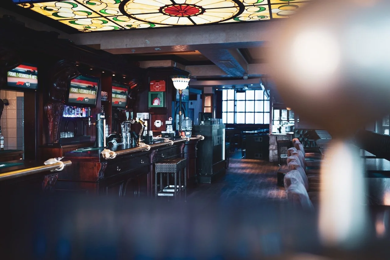 Bar-disk hos Metz Bergen med farget Tiffany-glasstak, mørkt panelert tre og TV-er som viser F1.